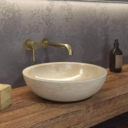 Lavabo basso marmo crema Karag Elena 40cm su piano legno: profilo ovale piatto con interno lucidato beige caldo e rubinetteria oro a muro