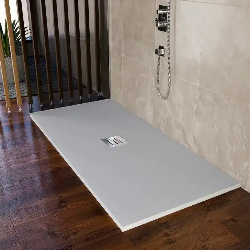 Una base doccia rettangolare di colore grigio chiaro con uno scarico quadrato centrale.
